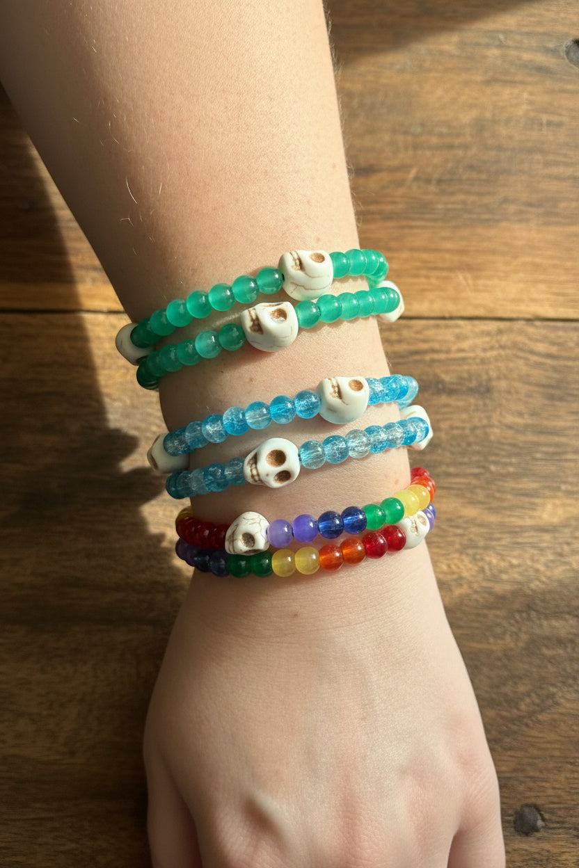 beaded stretch bracelets with skull beads, shown stacked on a person's wrist against a dark background.