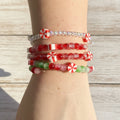 A stack of beaded stretch bracelets with red, white, and green candy-themed beads, shown worn on a person's wrist 