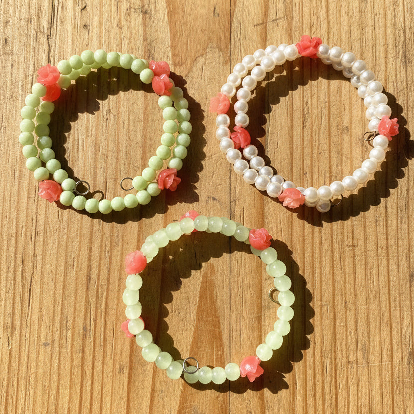 Three beaded stretch bracelets  One bracelet is made of light green beads with  flower charms.