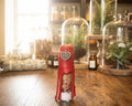 A small red  bottle standing on a wooden table 